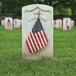 an american flag on a grave in a cemetery